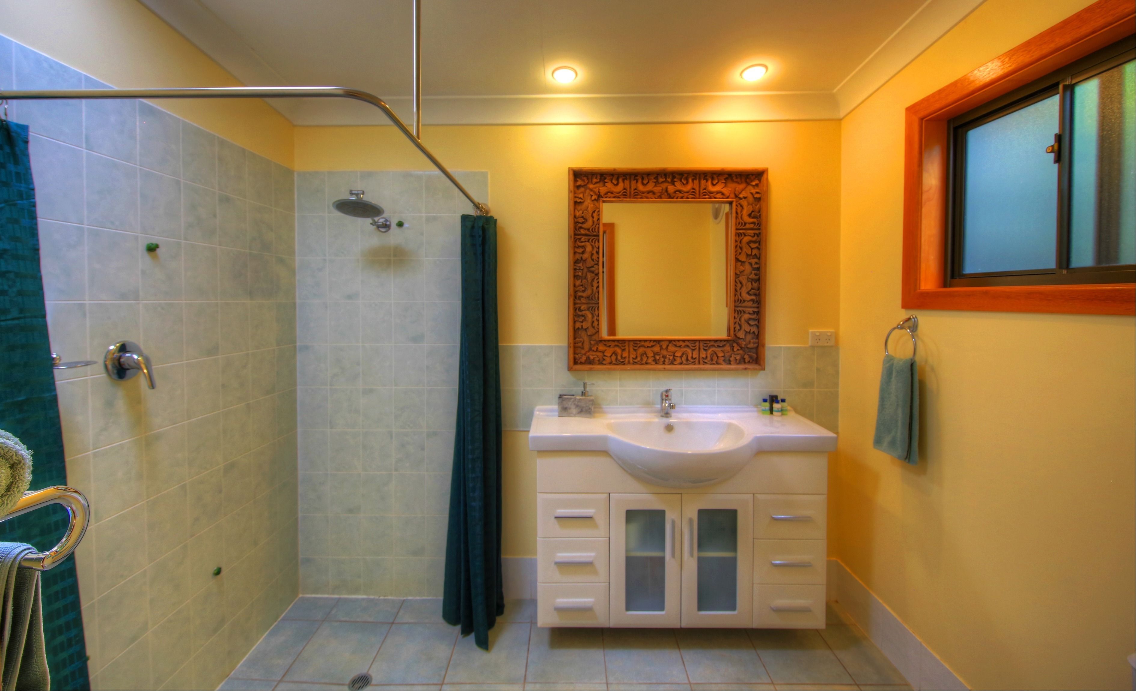 Un baño con ducha, lavamanos y tocador.