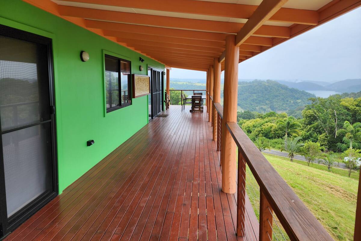 A wooden deck with a green wall and a view of the mountains.