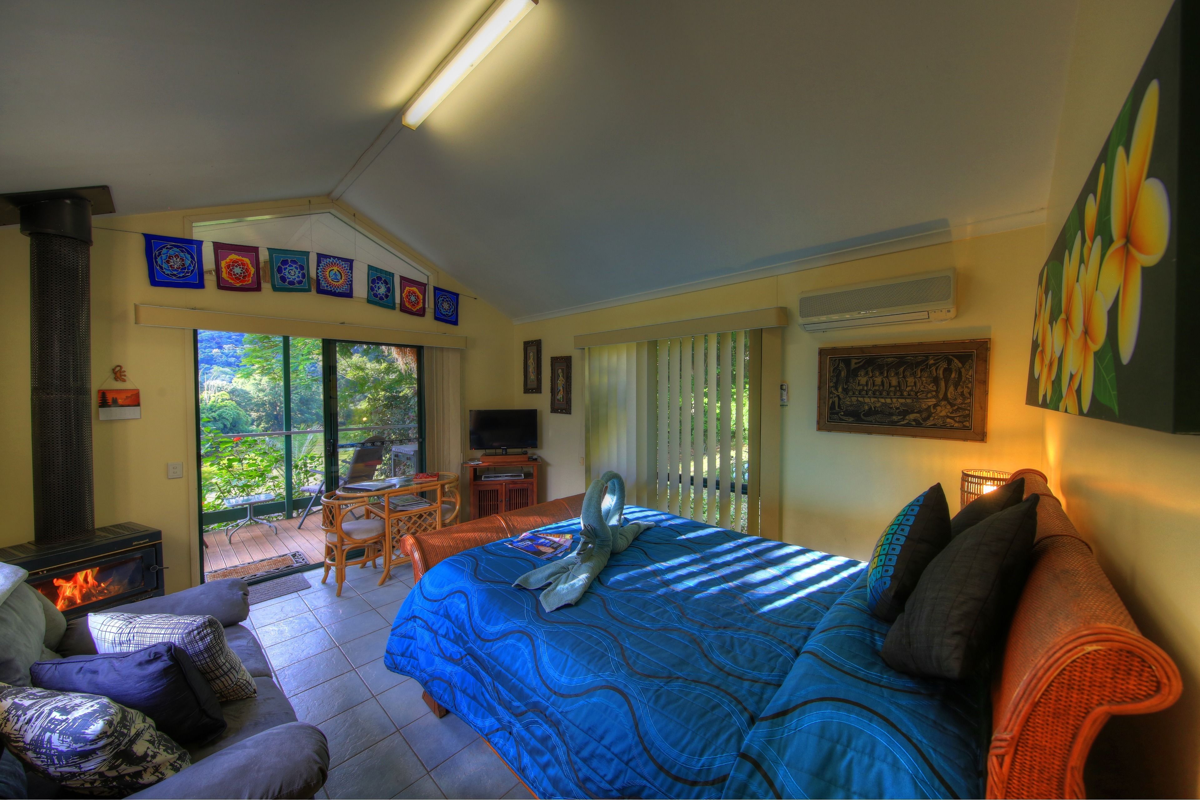 A bedroom with a bed, a sofa, a TV, and a fireplace.