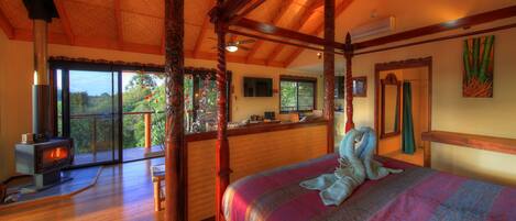 Un dormitorio espacioso con una cama grande, techo de madera y vistas al exterior.