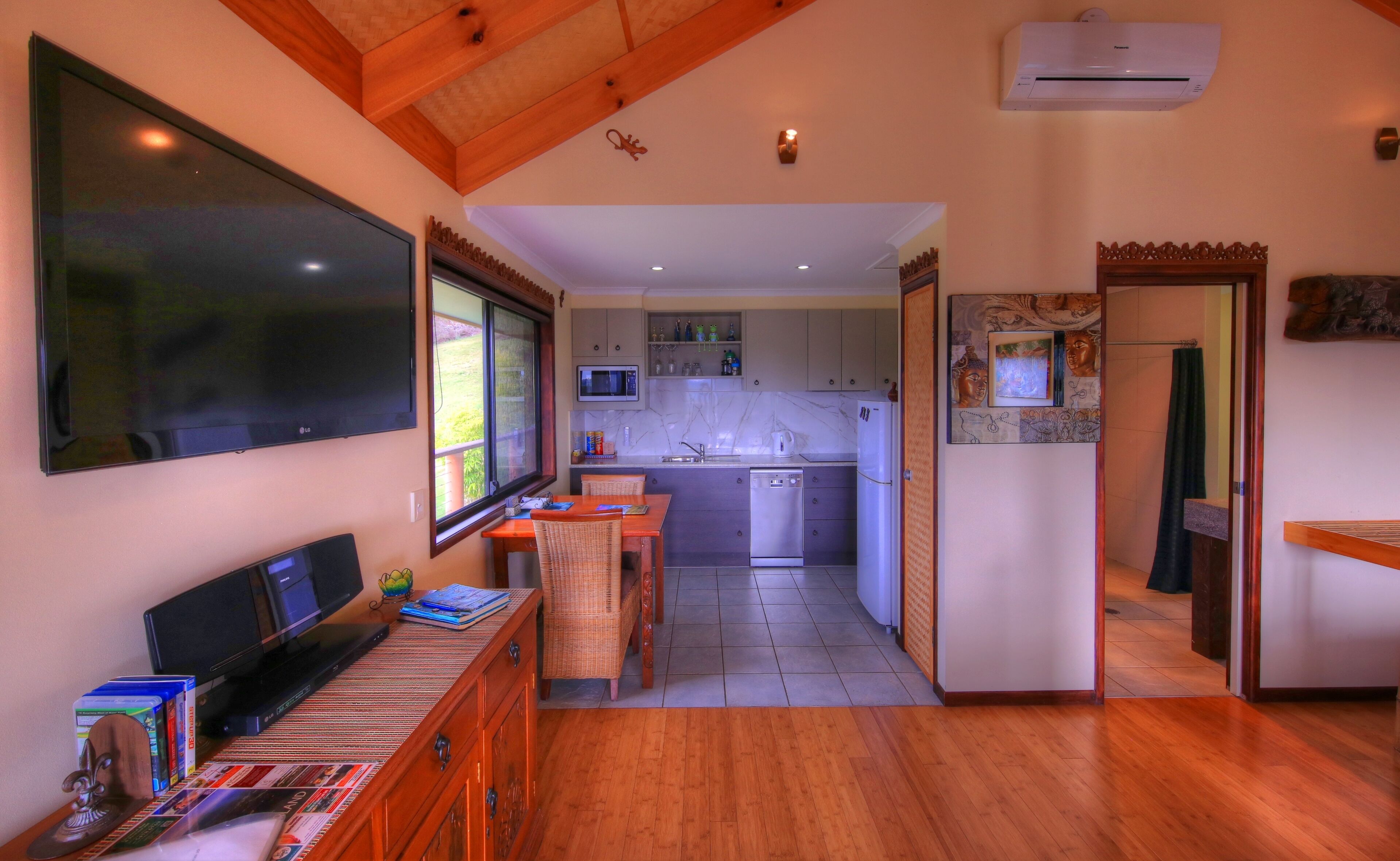 A compact kitchen with a dishwasher, microwave, and a window overlooking a garden.