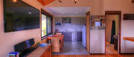 A compact kitchen with a dishwasher, microwave, and a window overlooking a garden.