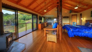 Quarto espaçoso com uma cama grande, uma mesa de jantar de madeira e vista para o exterior.
