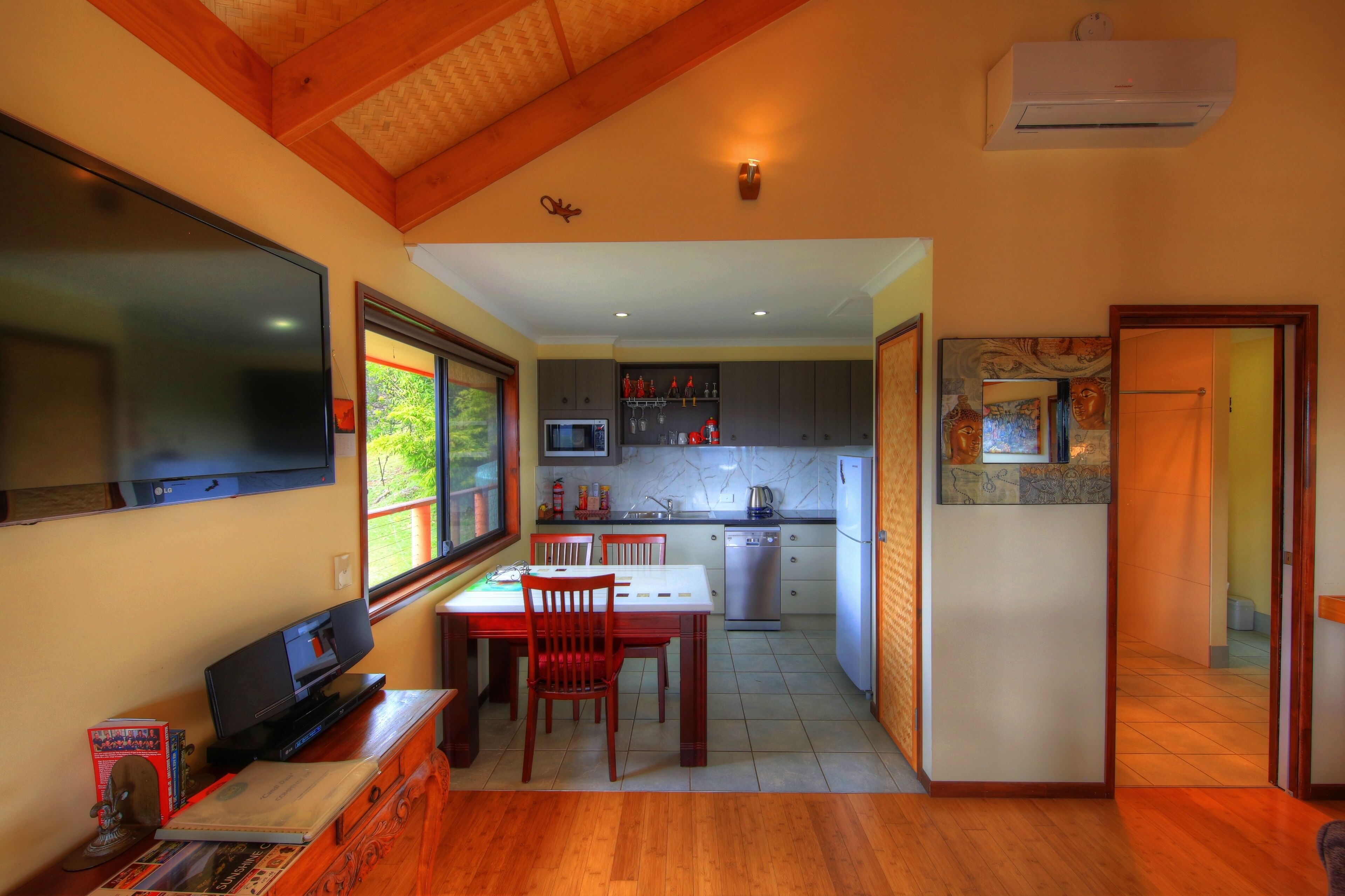 A compact kitchen with a microwave, stove, and sink, adjacent to a dining area with a table and chairs.