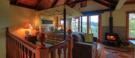 Una habitación con cama, sofá, chimenea y vistas al exterior.