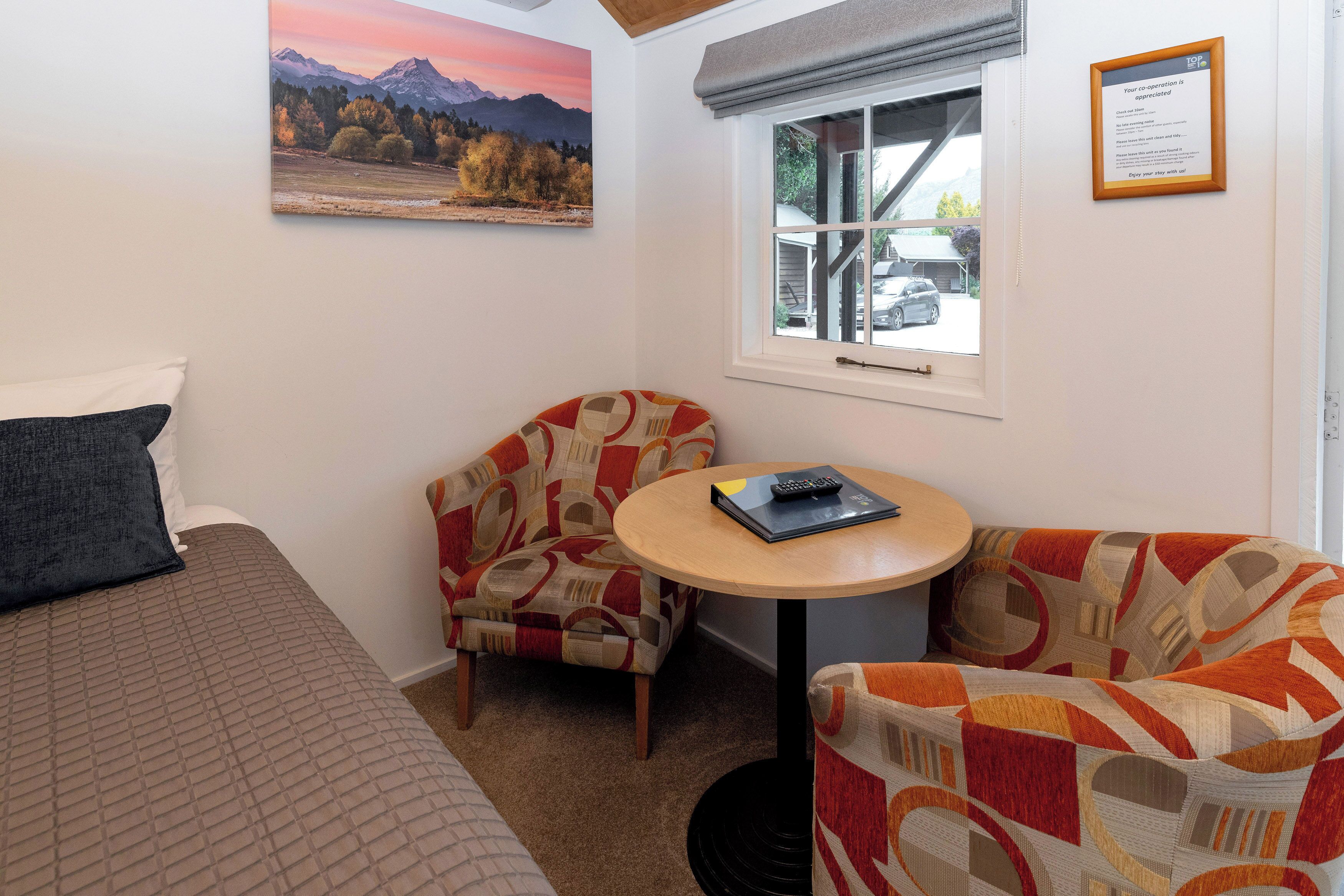 Une petite pièce confortable, avec un lit, une chaise, une table et une fenêtre.
