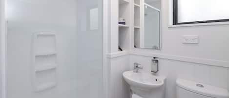 Un baño moderno con ducha, lavamanos e inodoro.