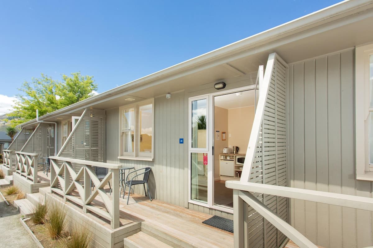 A row of cabins with a wooden deck, a covered outdoor seating area, and a sliding glass door entrance.