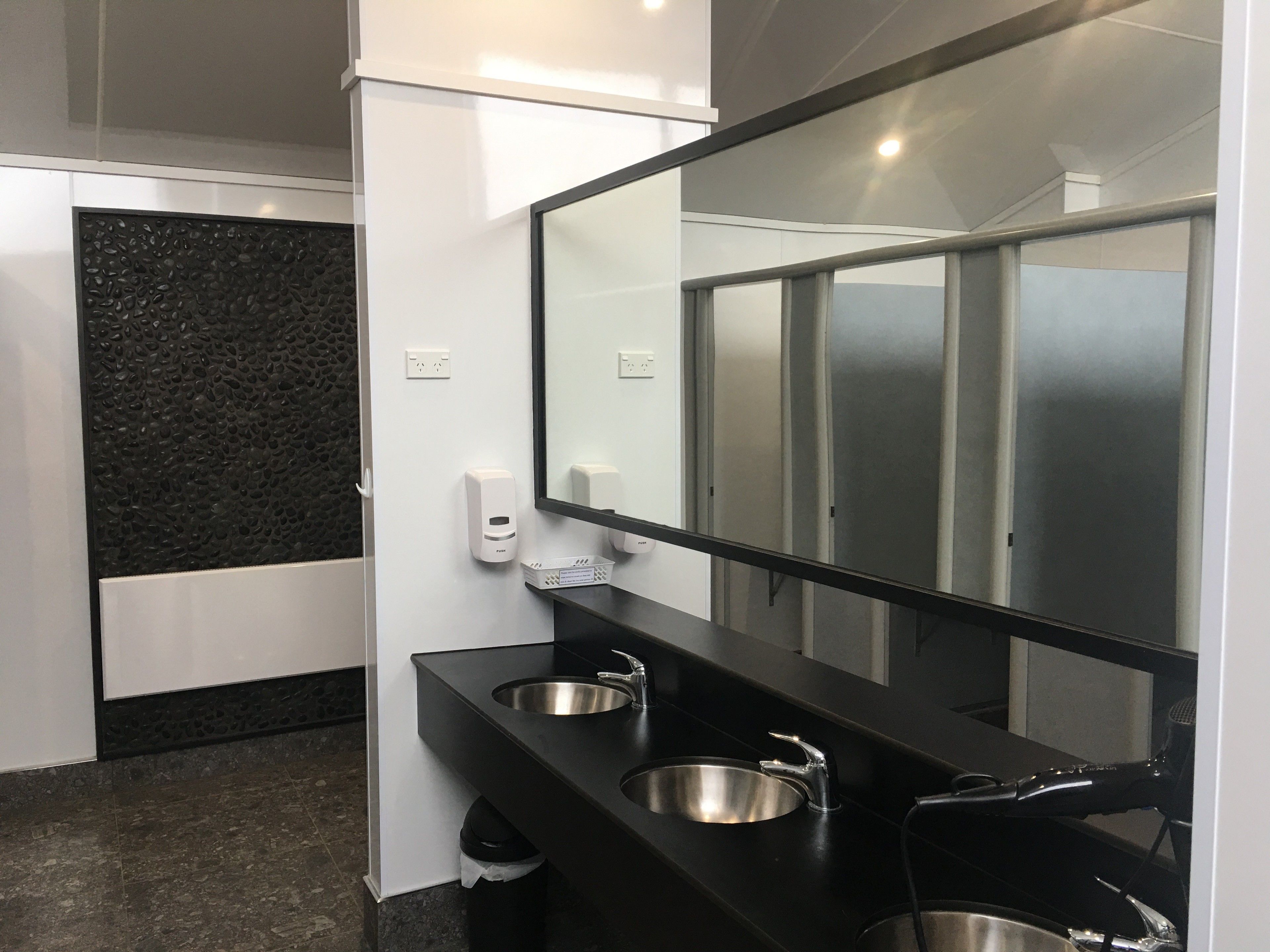 Un baño moderno con dos lavamanos, un espejo grande y una encimera negra.