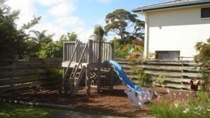 A residential area with a white house, a wooden deck, and a fenced yard. - The Peninsular Merimbula (Merimbula)