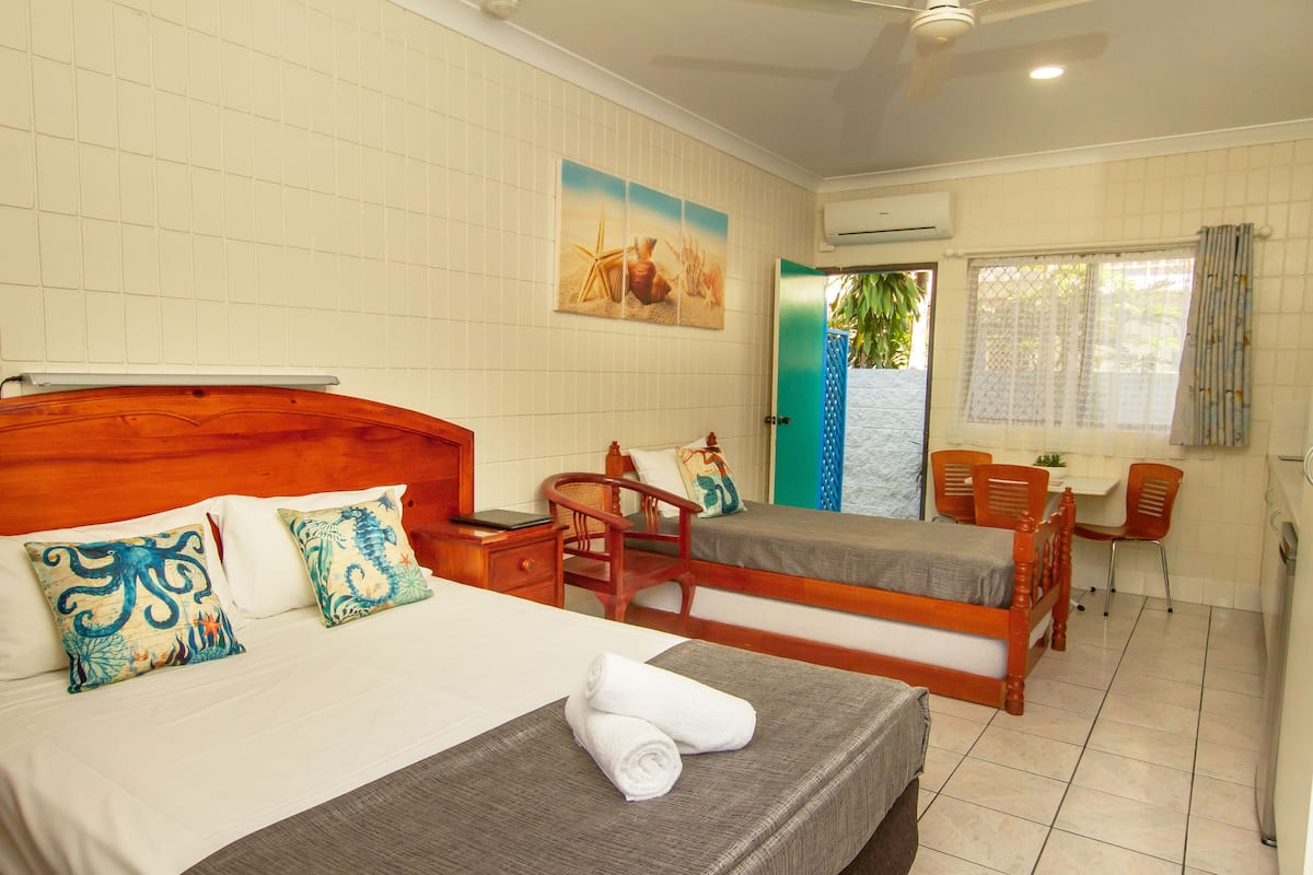 Quarto de hotel com duas camas de solteiro, uma escrivaninha e uma cadeira.