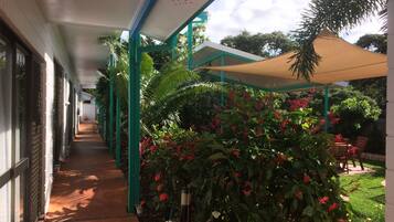 Stroll through lush gardens to a shaded seating area with a table and chairs.