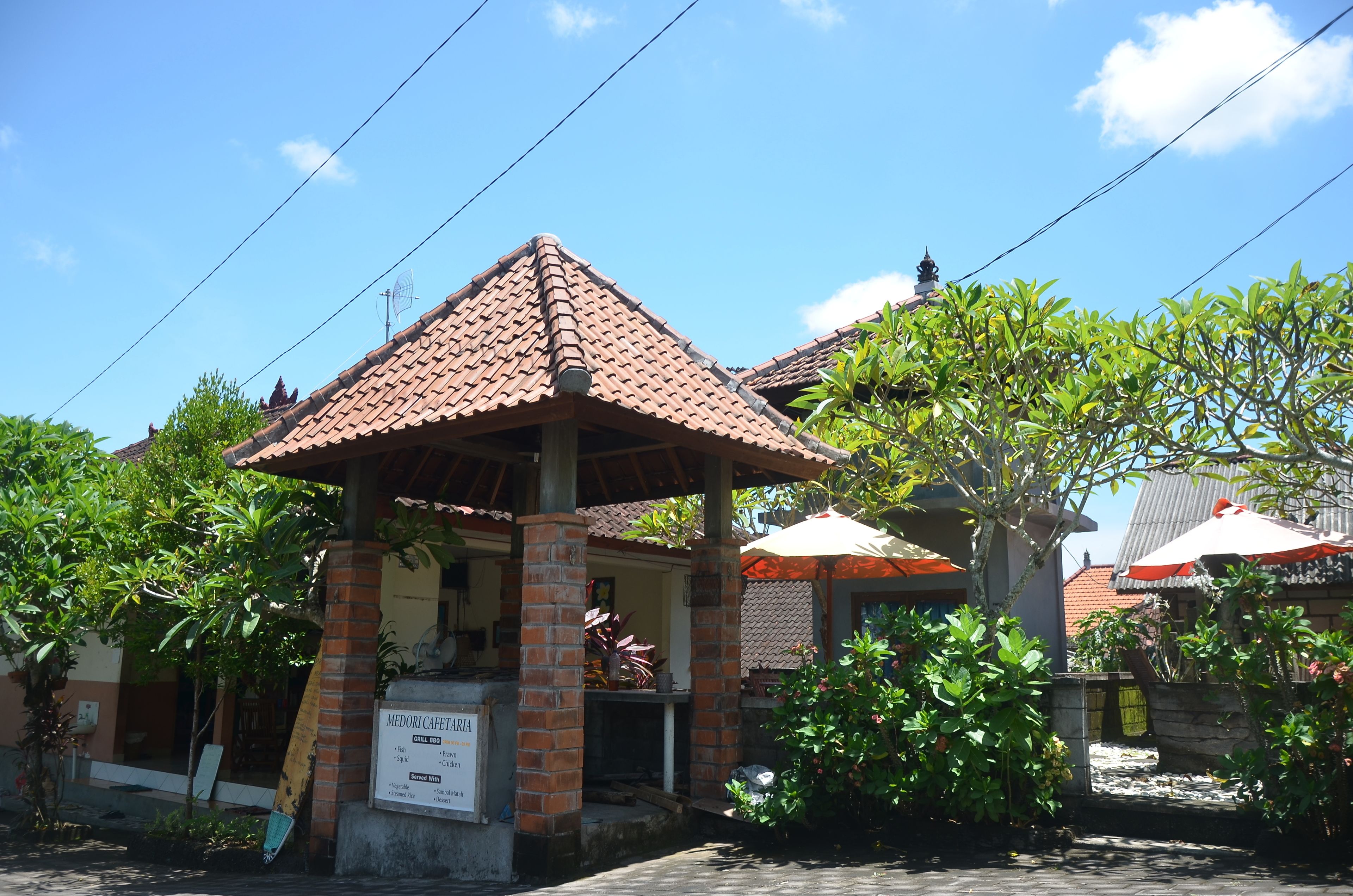 A traditional building with a tiled roof, a signboard, and surrounding greenery.