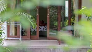 A room with a bed, a small table, and a plant. - Medori Putih Homestay (Pecatu)