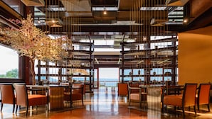 A spacious restaurant with a high ceiling, modern lighting, and a view of the sea. - Mountain Creek Golf Resort & Residences (Sikhio)