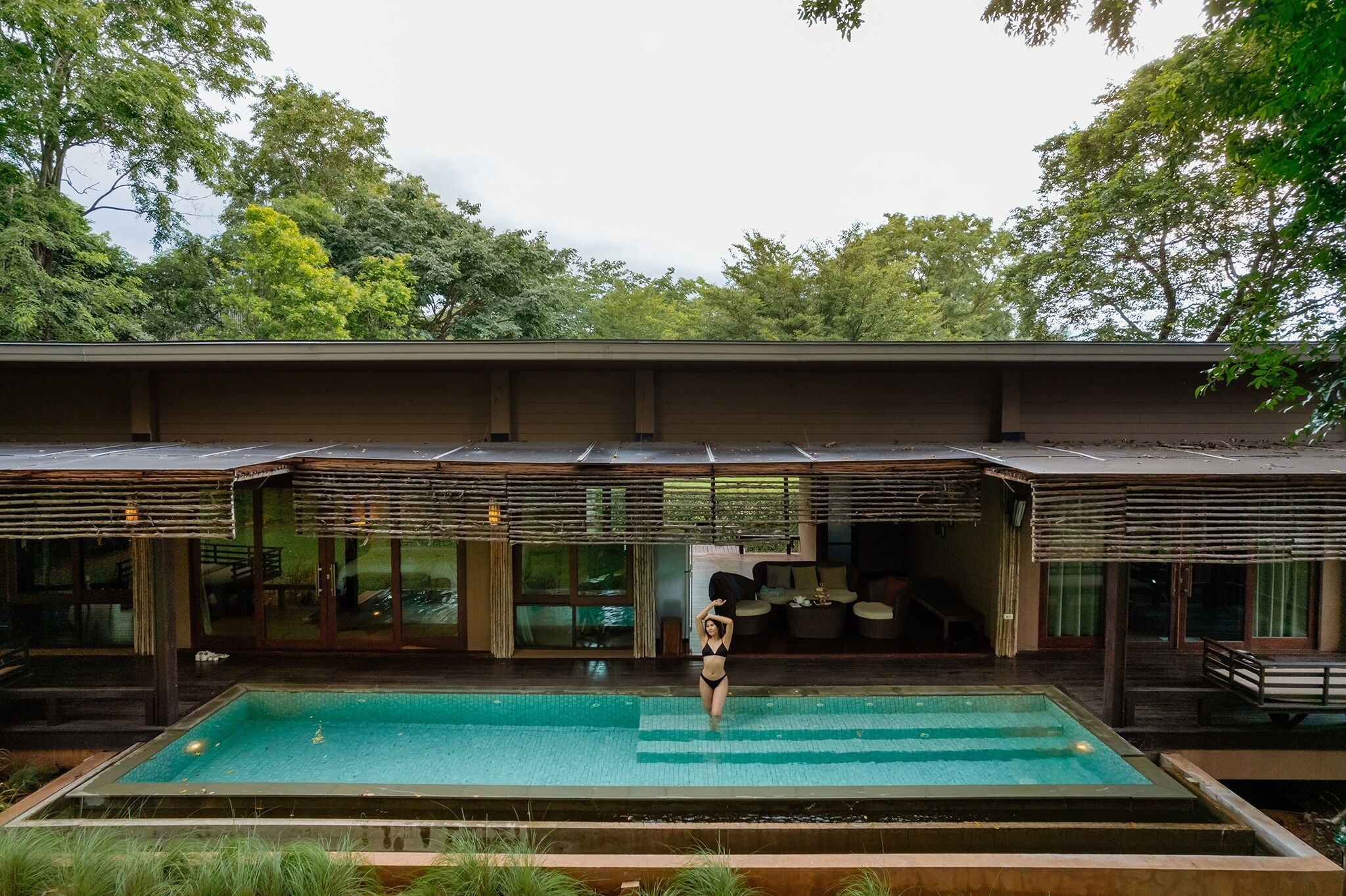 A modern building with a swimming pool, large windows, and a covered outdoor area.