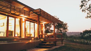 A modern building with large windows, a covered outdoor seating area, and a pathway leading to the entrance. - Mountain Creek Golf Resort & Residences (Sikhio)