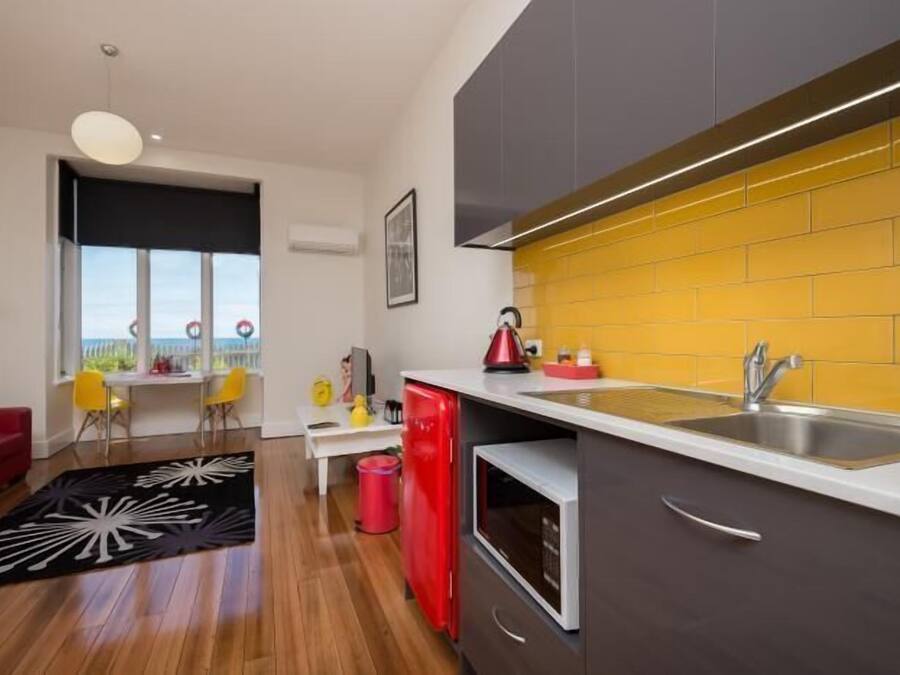 Una cocina moderna con un salpicadero amarillo, un refrigerador rojo y una encimera blanca.