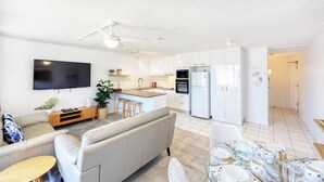 A modern apartment with a living room, kitchen, and dining area. - Merrima Court Holidays (Kings Beach)