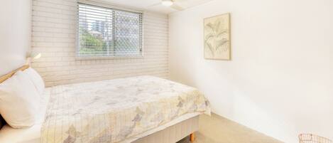 A bedroom with a bed, a window with blinds, a ceiling fan, and a wall-mounted picture.