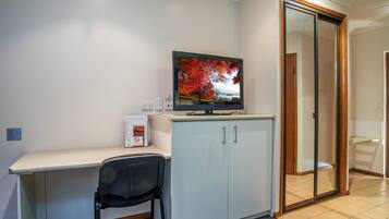 A small office space with a desk, chair, television, and a sliding glass door.
