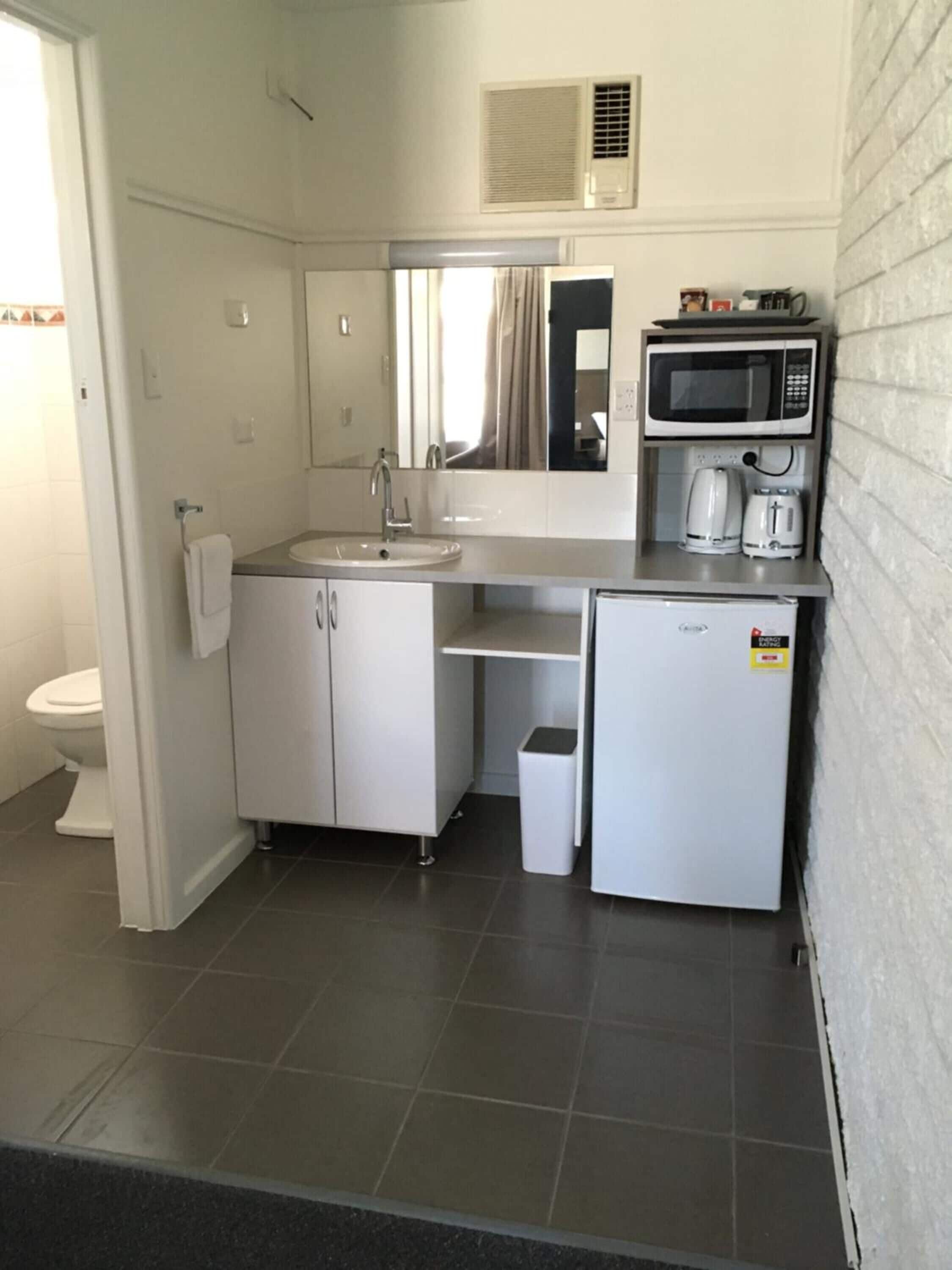 A compact kitchenette with a sink, microwave, and coffee maker.