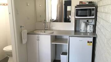 A compact kitchenette with a sink, microwave, and coffee maker.