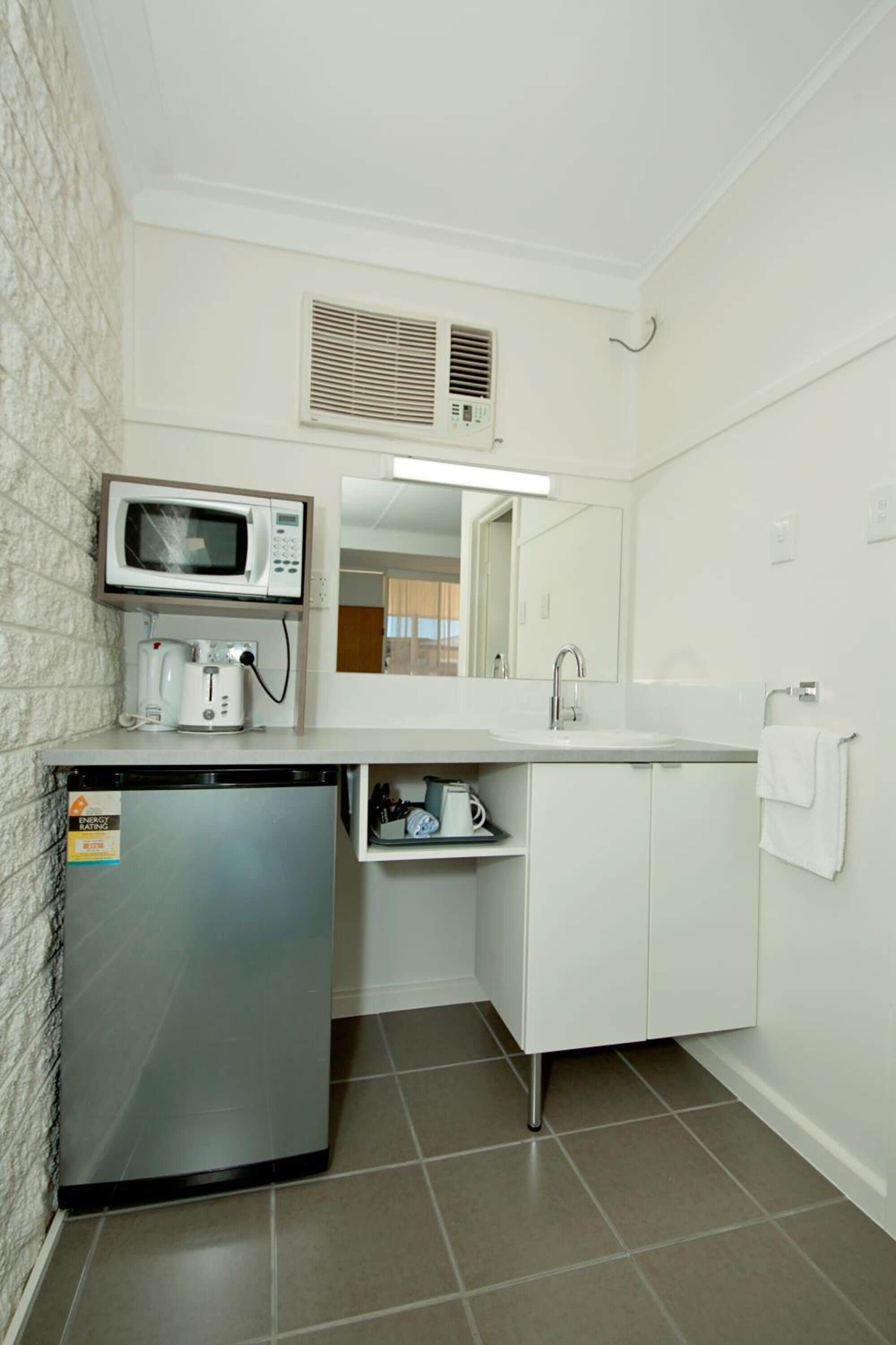 A compact kitchenette with a microwave, coffee maker, and a small refrigerator.