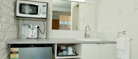 A compact kitchenette with a microwave, coffee maker, and a small refrigerator.