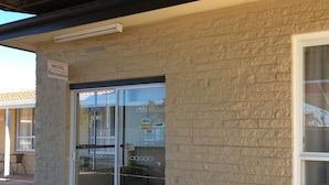 Mostrador de recepción de un motel con puerta de vidrio, un letrero que indica 'No se admiten mascotas' y un adhesivo de clasificación 'AAA'.