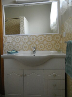 Baño con lavamanos, espejo y azulejos con diseño.