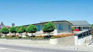 A residential building with a green roof, a staircase leading to the entrance, and a well-maintained garden with various plants and flowers. - Blue Dolphin Motel (Timaru)