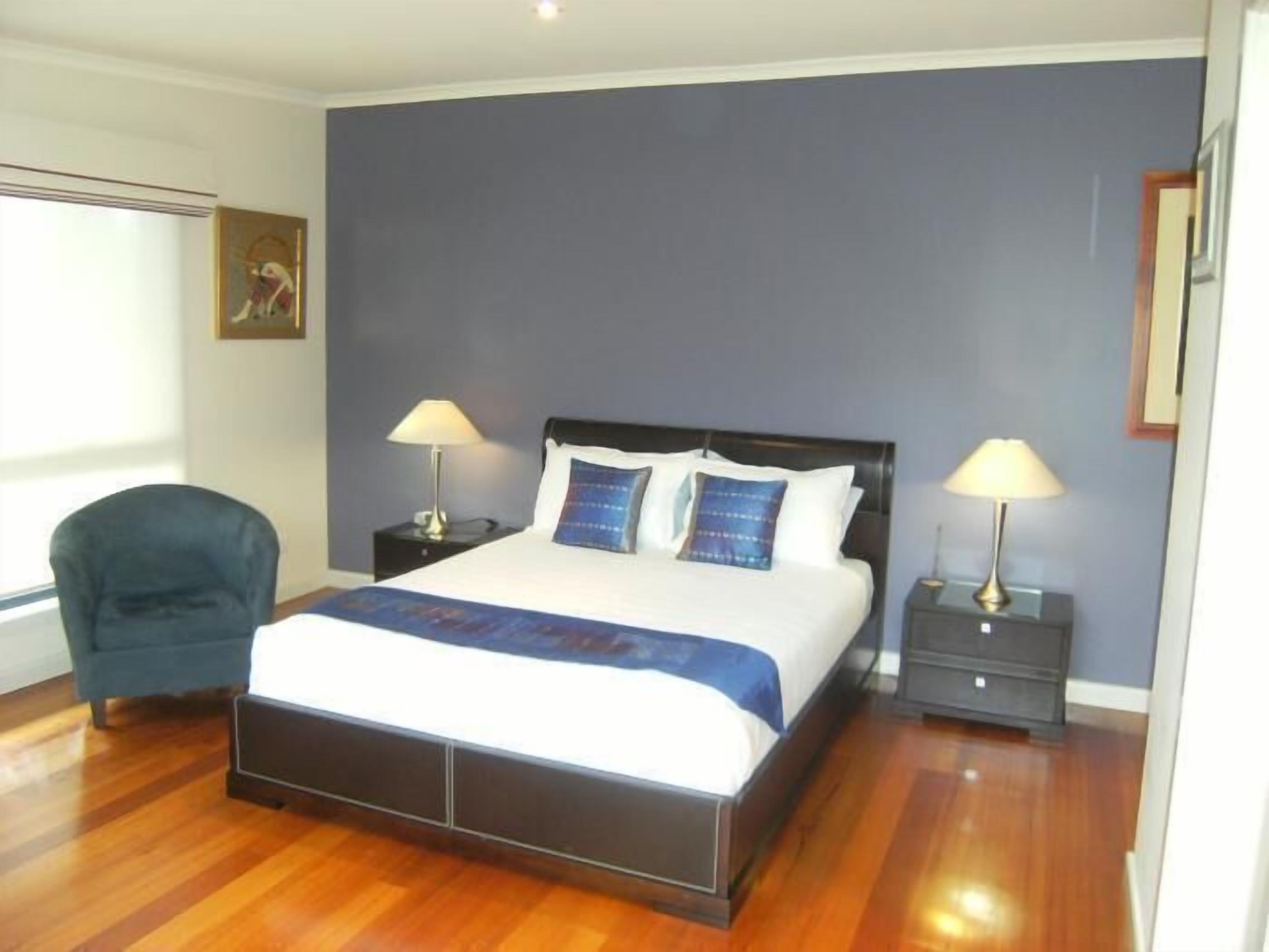 A bedroom with a bed, two bedside tables, a chair, and a window.