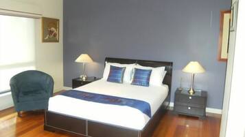 A bedroom with a bed, two bedside tables, a chair, and a window.