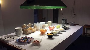 A buffet table with various food items and containers, including bowls of fruit and stacked plates. - Chalet Jindabyne (Jindabyne)