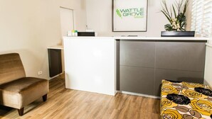 Un espace d’accueil avec un bureau blanc, une chaise marron et un coussin à motifs.