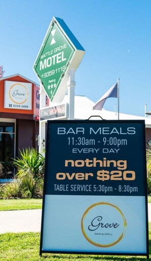 A motel sign with a bar and grill offering meals for $20 or less.