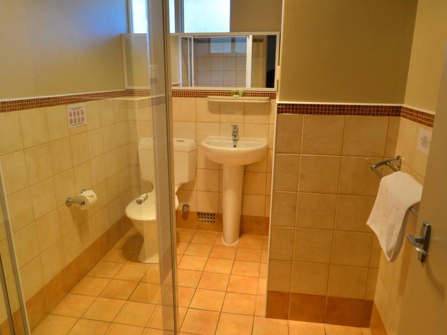 A bathroom with a glass shower enclosure, a toilet, a sink, and a towel rack.