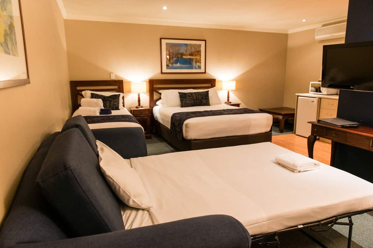Una camera d'albergo con due letti, una scrivania, una televisione e un quadro appeso al muro.