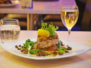 A plated dish with a glass of white wine and a glass of water on a table.