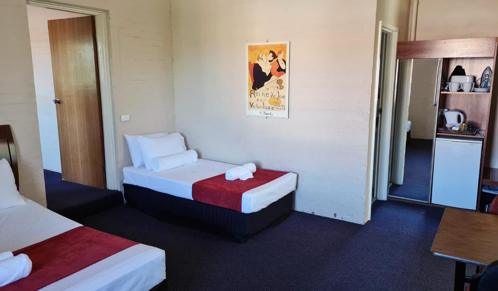 Una habitación de hotel con dos camas, una kitchenette pequeña y un cartel en la pared.