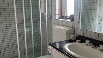 A bathroom with a glass-enclosed shower, a toilet, a sink, and a mirror.