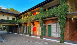 A hotel facade with ivy-covered columns, brick walls, and green doors. - Seaton Arms Motor Inn (Albury)
