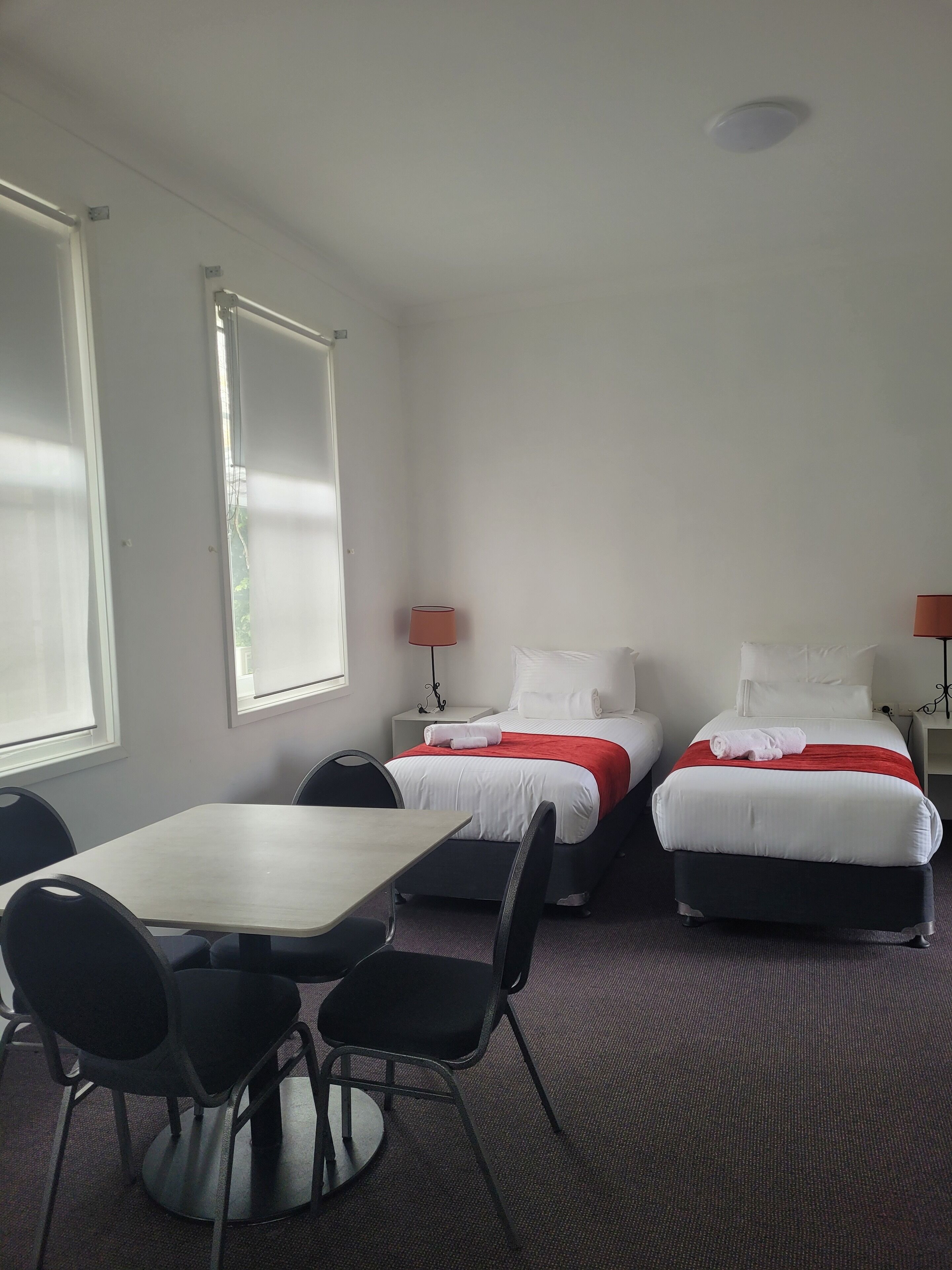 A hotel room with two beds, a table, and chairs.