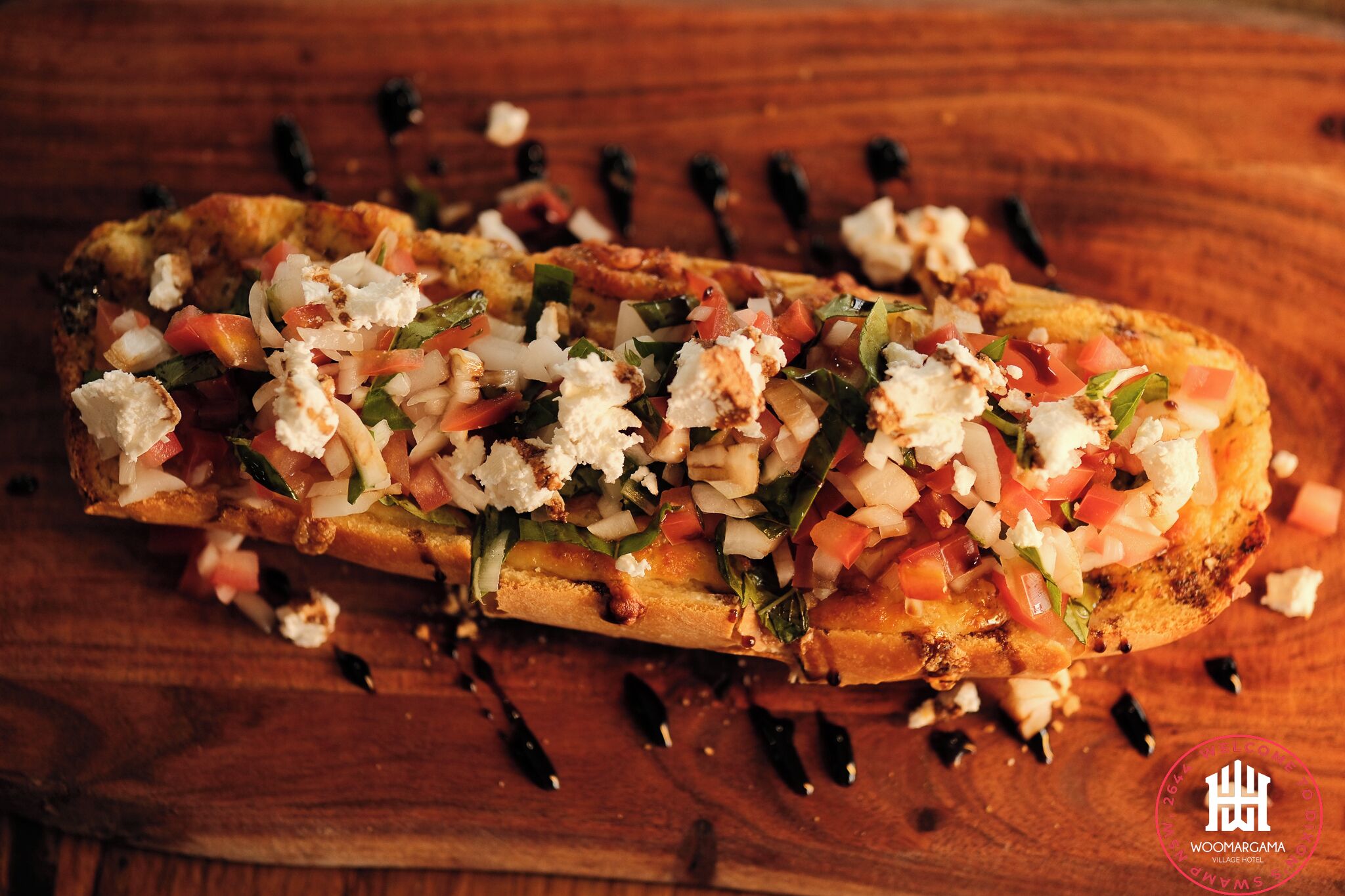 A grilled sandwich with toppings on a wooden board.