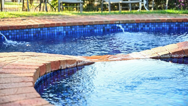 A swimming pool with a tiled edge and a brick border. - Woomargama Village Hotel Motel (Woomargama)