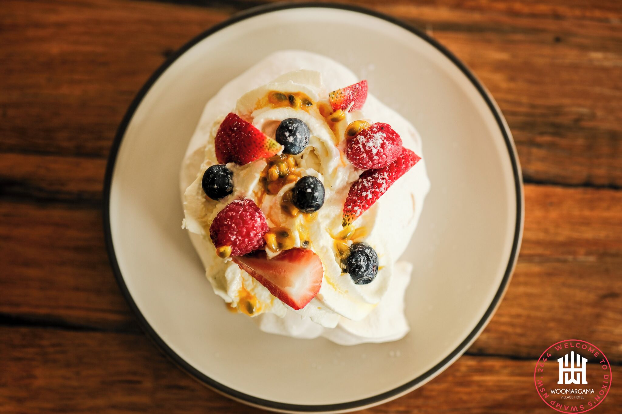 A dessert on a plate with strawberries, blueberries, and a drizzle of syrup.