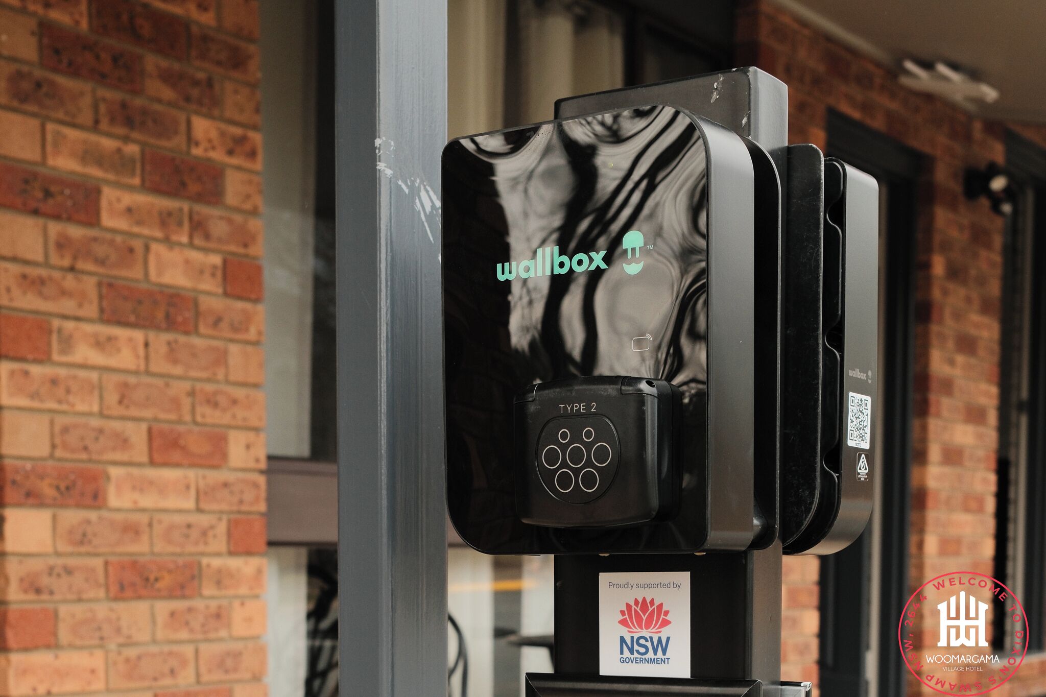 A wallbox with the 'wallbox' logo and a NSW Government sticker, indicating it is a public charging station.