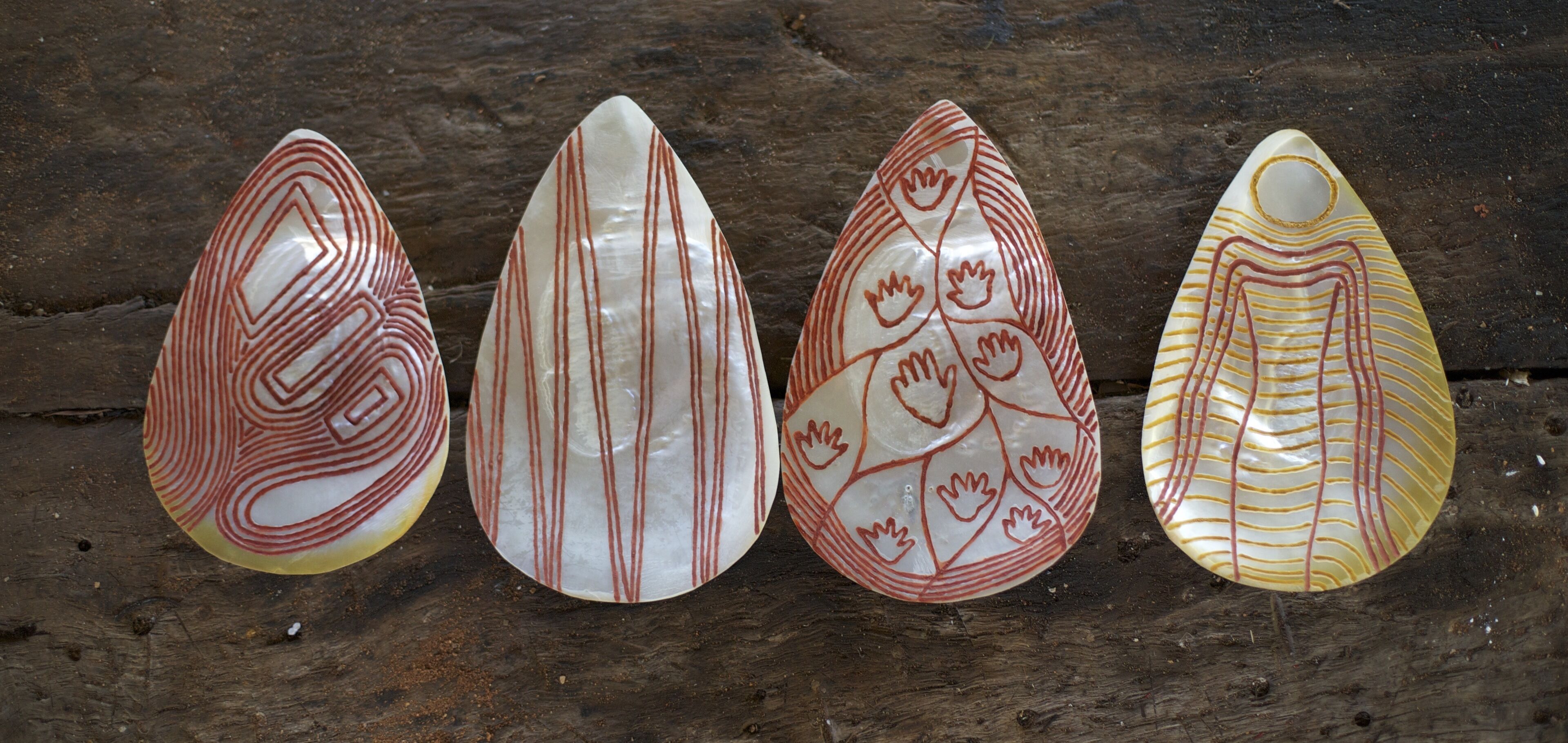 Vier decoratieve objecten met geometrische patronen op een houten ondergrond.