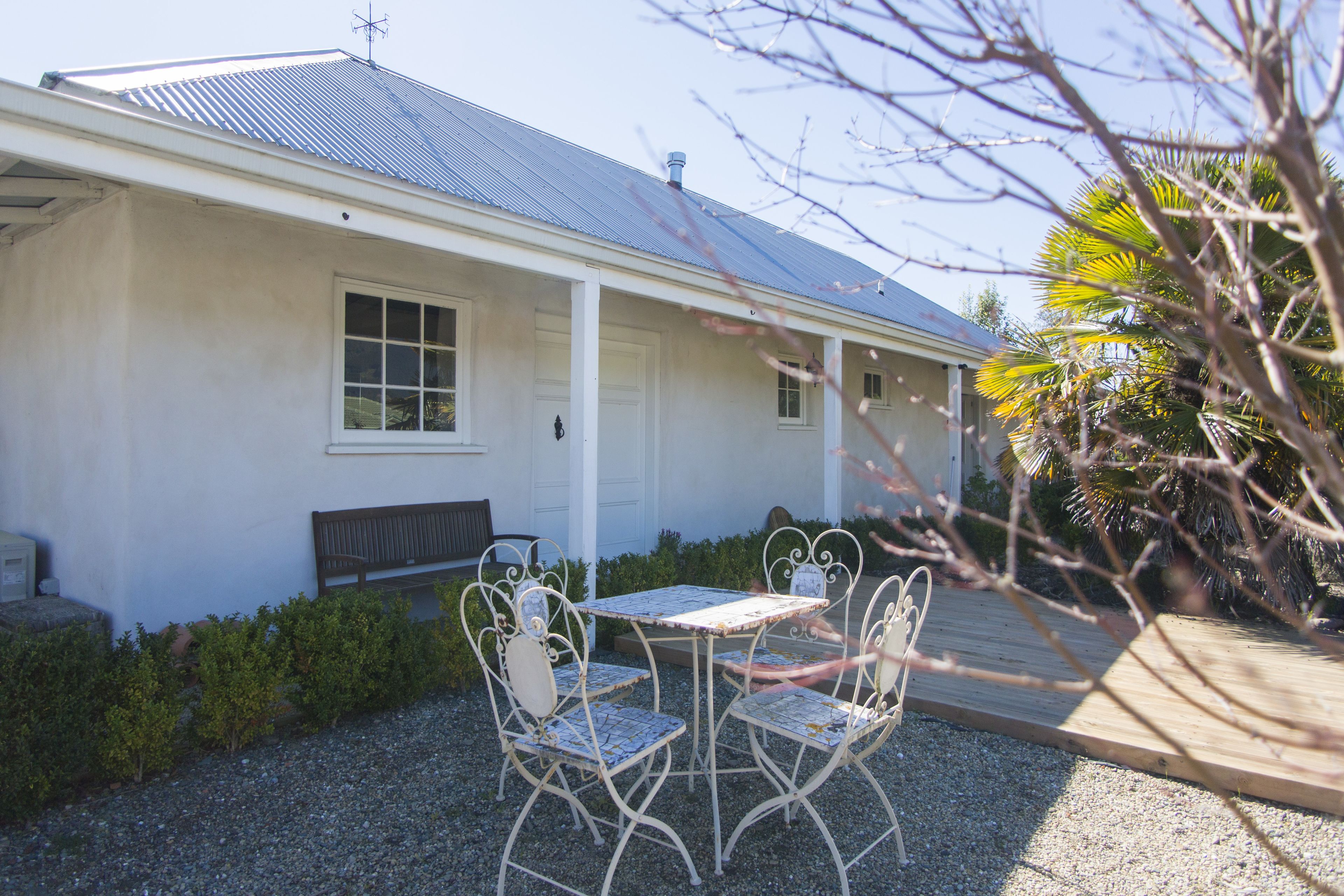 A building with a metal roof, a porch, and a gravel patio with metal chairs and a table.